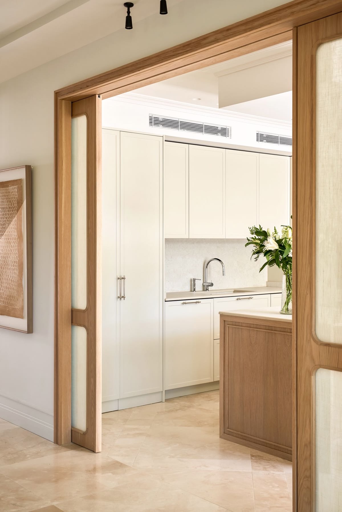 Wood double pocket doors with frosted glass panels opening into a modern kitchen