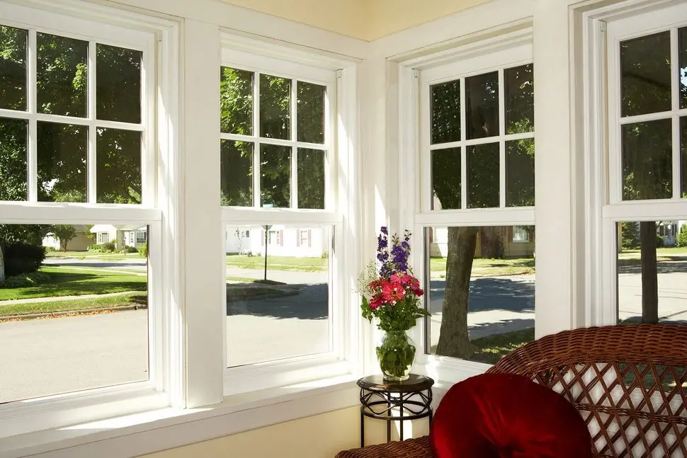 White double hung windows with divided light sashes in a bright residential sunroom